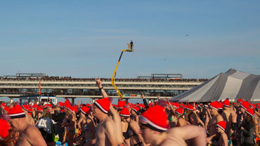 Niet alleen veel deelnemers bij deze nieuwjaarsduik, maar ook veel publiek: zelfs de Pier staat stampvol.